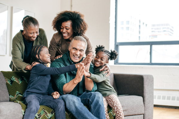 A black family playing and hugging on a sofa